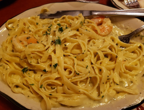 A plate of fettuccine pasta with shrimp in a creamy sauce, garnished with herbs.