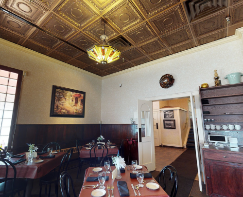 Cozy restaurant interior with wooden tables, elegant decor, and a vintage ceiling light.