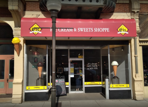 Exterior of an ice cream shop with a red awning, featuring ice cream cone signage and a welcoming entrance.