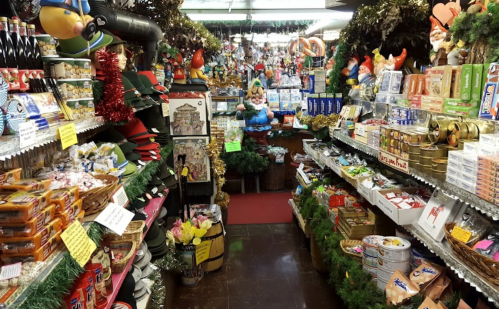 A festive shop aisle filled with holiday decorations, snacks, and gifts, adorned with greenery and colorful ornaments.