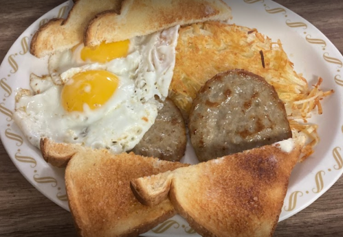 A plate with two fried eggs, hash browns, sausage patties, and two slices of toasted bread.
