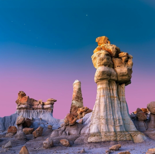 Unique rock formations under a twilight sky, showcasing vibrant colors and intricate textures in a desert landscape.