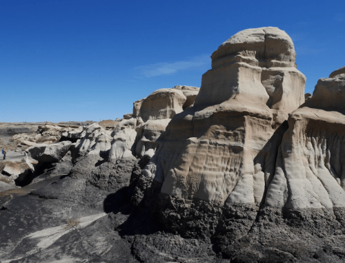 Rock formations with layered textures and a clear blue sky in the background, showcasing natural erosion patterns.