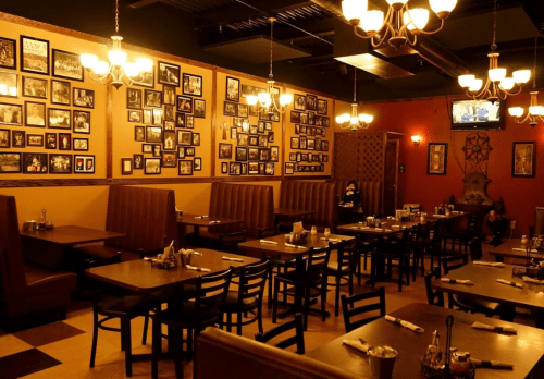 Cozy restaurant interior with wooden tables, booths, and walls adorned with framed photos and warm lighting.