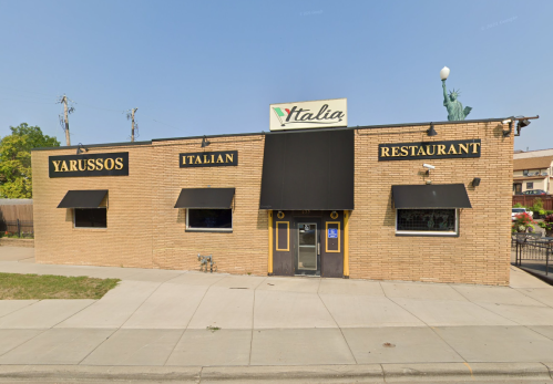 Exterior of Yarussos Italian Restaurant, featuring a brick facade, black awnings, and a sign reading "Italia."