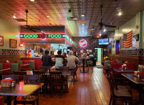 A cozy diner interior with colorful neon signs, tables, and patrons enjoying their meals.