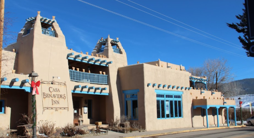 A southwestern-style inn with adobe architecture, blue accents, and a festive wreath on the entrance.