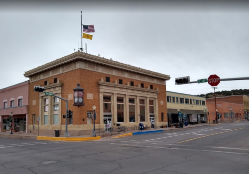 Historic building with a flag, street signs, and a clock in a small town setting on a cloudy day.