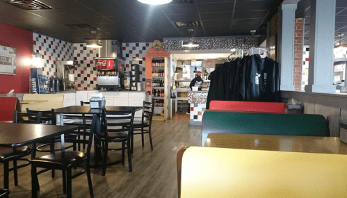 A cozy restaurant interior with colorful booths, black chairs, and a counter in the background.