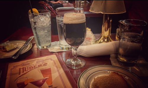 A table setting at a restaurant featuring drinks, a menu, and a plate with food, creating a cozy dining atmosphere.