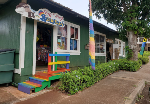 Colorful entrance of the Big Wind Kite Factory, featuring a rainbow staircase and lush greenery outside.