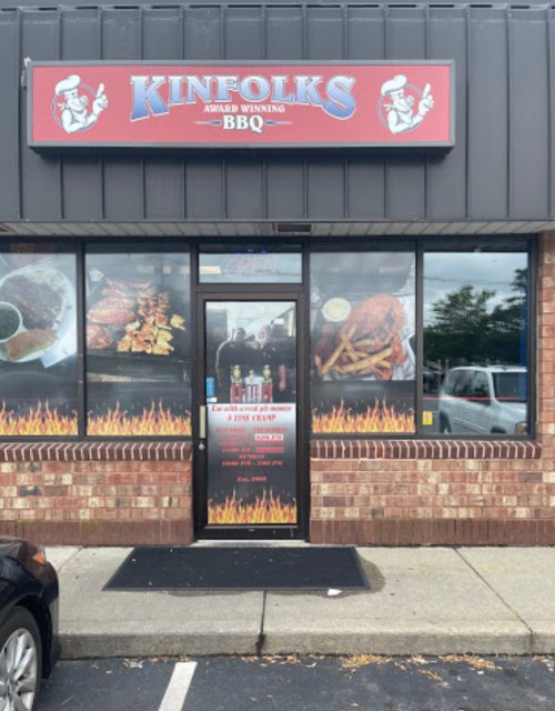 Exterior of Kinfolks BBQ restaurant featuring a sign, menu display, and a welcoming entrance.