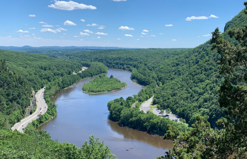 A scenic view of a winding river surrounded by lush green hills under a clear blue sky.