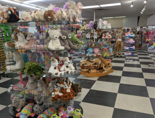 A colorful toy store interior filled with plush animals, toys, and a wooden motorcycle display.