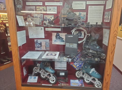 Display case featuring inline skates, historical documents, and memorabilia related to roller sports.