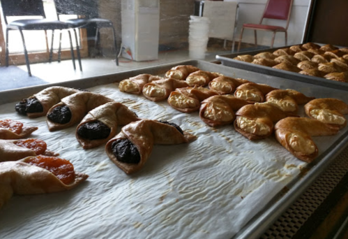 A tray of freshly baked pastries, including fruit-filled and chocolate-filled options, on parchment paper.