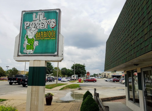 Sign for "Lil' Porgy's Barbeque" outside a restaurant, with a cloudy sky and nearby parking lot visible.
