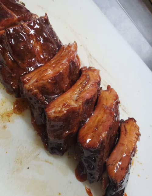 Sliced, glazed barbecue ribs arranged neatly on a cutting board, showcasing a rich, caramelized exterior.