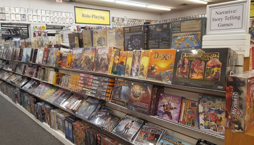 A well-stocked shelf of role-playing and storytelling games in a game store, featuring various colorful game boxes.