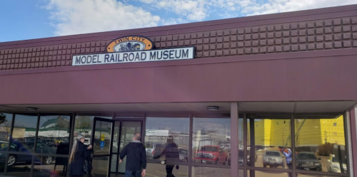 Entrance of the Twin City Model Railroad Museum, featuring a sign and visitors approaching the door.