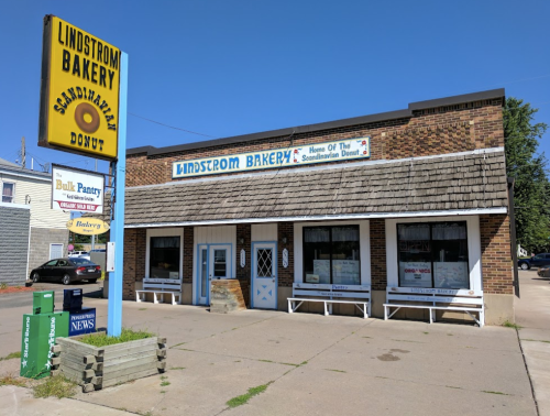 Exterior of Lindstrom Bakery, featuring a sign for Scandinavian donuts, with a brick facade and clear blue sky.
