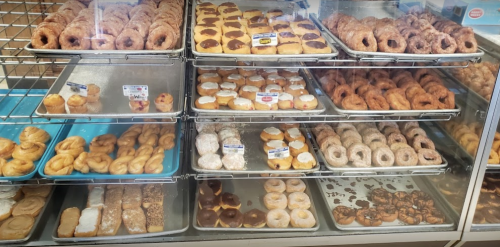 A display case filled with various types of donuts, including glazed, chocolate-covered, and cream-filled options.