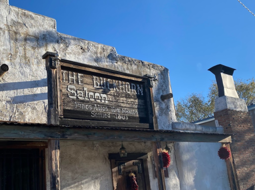Sign for "The Buckhorn Saloon" on a rustic building with a clear blue sky in the background.