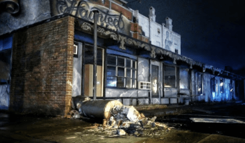 Abandoned building with graffiti, a toppled trash can, and dim lighting, creating a haunting atmosphere.
