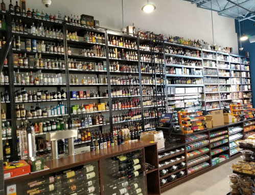 A well-stocked liquor store with shelves filled with various bottles of alcohol and a display of snacks.