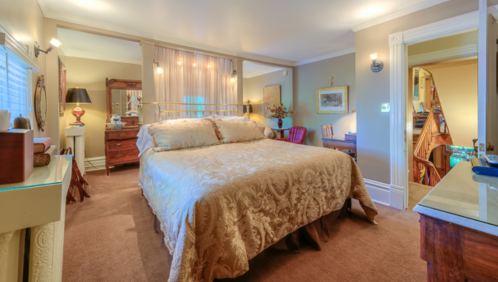 Cozy bedroom with a large bed, warm lighting, and elegant decor, featuring a staircase in the background.