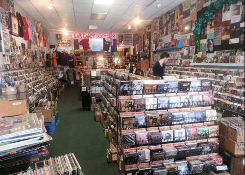 A vibrant record store filled with shelves of vinyl records, CDs, and music memorabilia, with a customer browsing.