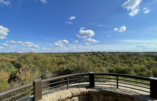 A scenic view of a lush green landscape under a bright blue sky with fluffy white clouds.