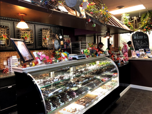 A colorful candy shop display featuring a glass case filled with various chocolates and sweets.