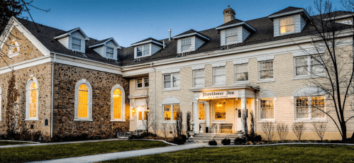 A charming inn with a stone and cream exterior, featuring large windows and a welcoming entrance.
