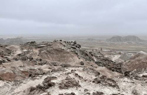 A barren landscape with rocky hills under a cloudy sky, showcasing a desolate, rugged terrain.