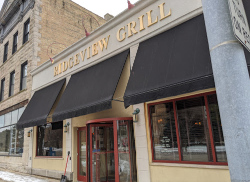 Exterior of Ridgeview Grill, featuring a large sign, awnings, and a snowy sidewalk in front of a historic building.