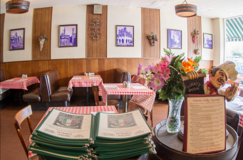 Cozy restaurant interior with checkered tablecloths, floral arrangements, and a menu display featuring daily specials.