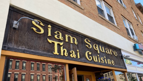 Sign for "Siam Square Thai Cuisine" on a building exterior, featuring decorative lettering.