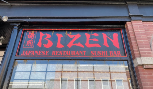 Sign for Bizen, a Japanese restaurant and sushi bar, featuring bold red lettering on a black background.