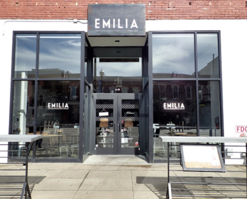 Exterior view of a restaurant named "Emilia," featuring large windows and a modern design.