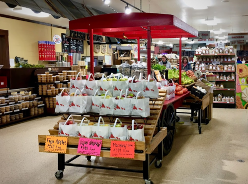 A vibrant market display featuring fresh produce, including apples and various vegetables, on a wooden cart.