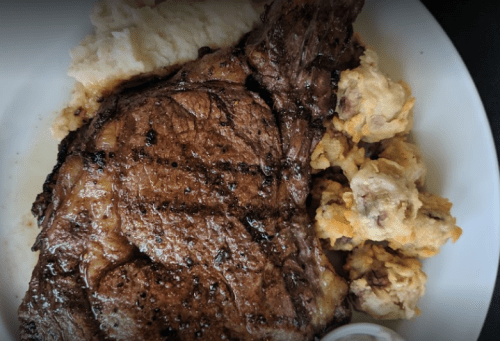 A plate featuring a grilled steak, creamy mashed potatoes, and savory stuffing.