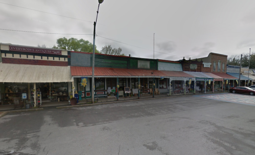 A street view of a row of antique shops with awnings and a cloudy sky overhead.