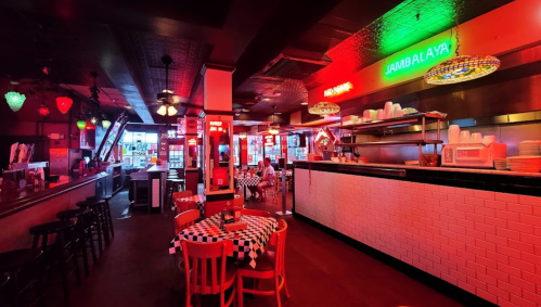A vibrant restaurant interior with neon lights, checkered tables, and a cozy atmosphere.