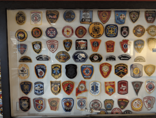A display case filled with various colorful patches from fire departments and emergency services.