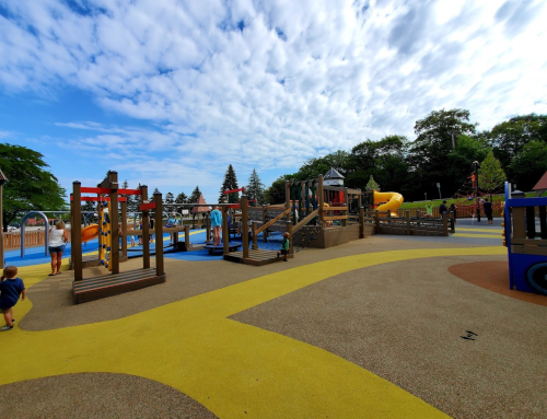 A colorful playground with slides, climbing structures, and children playing under a partly cloudy sky.