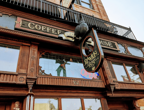 A vintage-style coffee house with a wooden facade and a hanging sign that reads "Ramen" and "Open."