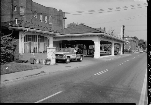Historic building with a tiled roof, truck parked outside, and street view in a black-and-white photograph.