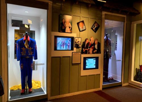 Display of colorful suits in glass cases, with framed photos on the wall showcasing various events and personalities.