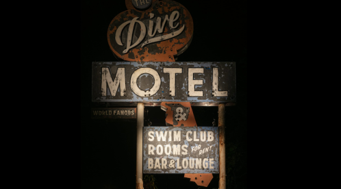 A vintage motel sign reading "The Dive Motel" with additional signs for a swim club and bar/lounge.